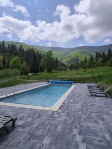 a swimming pool with chairs and mountains in the background at Під Горбком in Bukovets
