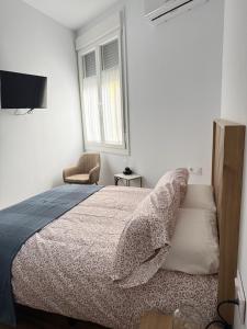 a white bedroom with a bed and a chair at Rincon de Toledillo in Plasencia