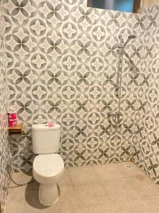 a bathroom with a toilet and a tile wall at Dewa Bungalows, A Balinese House and Art Gallery in Ubud +41 photos