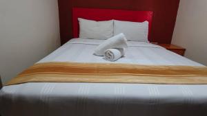 a bed with a red headboard with a towel on it at HWKl in Kuala Lumpur