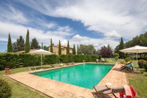 a swimming pool in a yard with chairs and umbrellas at Villa Campriano by VacaVilla in Pienza