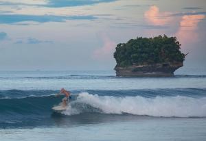 a man riding a wave on a surfboard in the ocean at Surf Front Villa Samar in Maydolong
