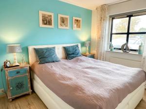 a bedroom with a bed with blue walls and a window at Villa Relax Ooghduyne - Dünen Golf und Spa bei Beach & more in Julianadorp +30 photos
