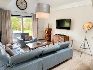a living room with a blue couch and a tv at Villa Relax Ooghduyne - Dünen Golf und Spa bei Beach & more in Julianadorp