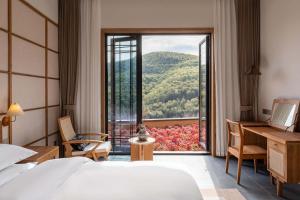 a bedroom with a bed and a desk and a large window at ALOR VALLEY HUZHOU in Huzhou
