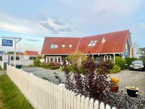 a house with a red roof and a white fence at Rørvig Bed & Kitchen in Rørvig