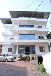a white building with a car parked in front of it at Nova Saara Palace in Kannur