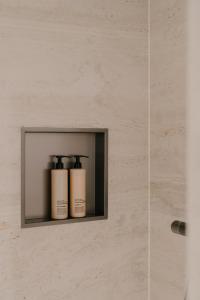 two shampoo bottles on a shelf in a bathroom at Boutique Hotel Herbergh Amsterdam Airport FREE PARKING in Badhoevedorp