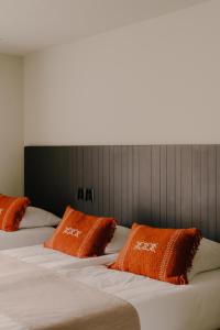 two beds with orange pillows sitting next to each other at Boutique Hotel Herbergh Amsterdam Airport FREE PARKING in Badhoevedorp