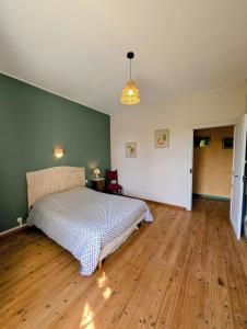 a bedroom with a bed and a wooden floor at L'Ecrin de Pommayrac - Appartement Nature, au coeur d'un centre équestre in Verzeille