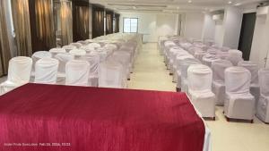 a row of white tables and chairs in a room at Hotel Pride Executive in Satara