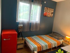 a small bedroom with a bed and a red refrigerator at Villa ALoha in Carcans