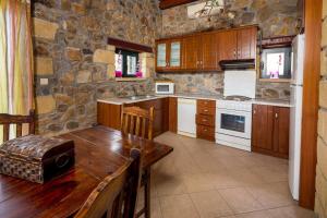 a kitchen with a wooden table and a stone wall at Villa Kimothoe with Private Pool, only 20 min to Elafonissi Beach in AmigdhalokeFálion