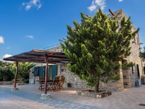 AmigdhalokeFálion的住宿－Villa Kimothoe with Private Pool, only 20 min to Elafonissi Beach，房屋前的树,带桌椅