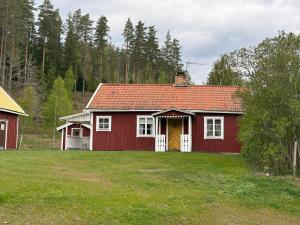 a red house with a yellow door in a yard at Ytterbo in Hultsfred