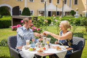a man and woman sitting at a table eating food at Schlosshotel Mondsee in Mondsee
