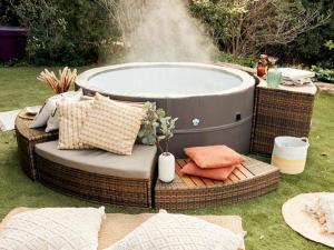 a hot tub sitting next to a wicker chair next to a wicker at chambre d'hôtes 25 M2 privé , parking, jardin, piscine, spa, barbecue Ruoms 2 in Ruoms