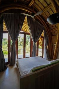 a bed in a room with windows and a ceiling at Mandala Eco Resort Lombok in Selong Belanak