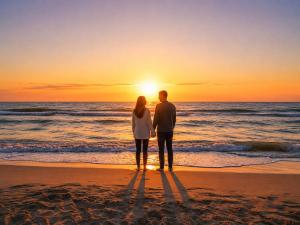 a couple standing on the beach watching the sunset at Mielnova Adults Only Jacuzzi & Sauna Apartamenty in Mielno