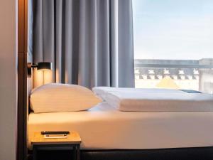 a bed in a hotel room with a window at B&B HOTEL Gütersloh in Gütersloh