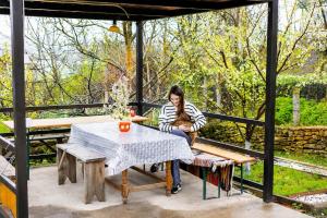 a woman sitting at a table on a patio at Casa Boierului (Viscauti) in Vîşcăuţi