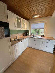 a kitchen with white cabinets and a wooden ceiling at Ferienhaus Paschelke in Friedrichskoog-Spitze