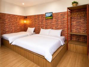 two beds in a room with a brick wall at YARA - Stay & Coffee in Mỹ Ðuc