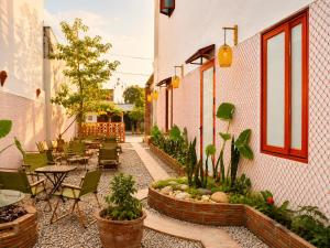 an outdoor patio with tables and chairs and plants at YARA - Stay & Coffee in Mỹ Ðuc