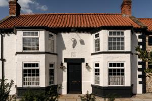 a white house with a red roof and a black door at The General Tarleton in Knaresborough