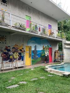 a mural on the side of a building with a pool at Bali Bobo Hostel in Jimbaran