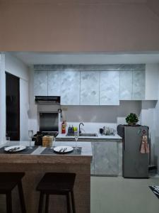 a kitchen with a refrigerator and a counter with stools at The Lake Haus Cebu in Lapu Lapu City