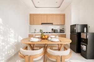 a kitchen with a wooden table and a black refrigerator at Ruana Villa Pererenan in Munggu