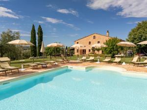 a pool with chairs and umbrellas in front of a house at Casalantico in Corinaldo