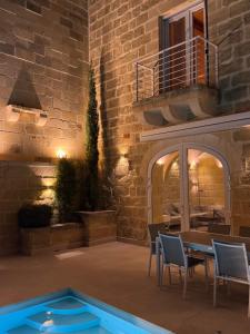 a patio with a table and chairs in front of a building at Villa La Mola Gozo Luxury Villa with Private Pool & Sunset Views in Għasri