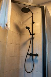 a shower with a shower head in a bathroom at Restaurant & Hotel De Jaeger in Ruurlo