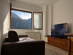 a living room with a couch and a large window at Foppolo GH in Foppolo