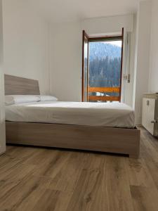a bedroom with a large bed with a large window at Foppolo GH in Foppolo