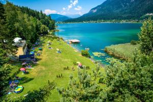 a group of people on the grass near a lake at Hotel Samerhof - Badestrand inklusive in Tröpolach
