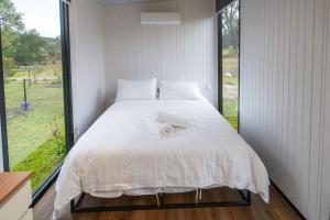 a bedroom with a white bed with a large window at Sparkling Tiny House by Tiny Away in Windeyer