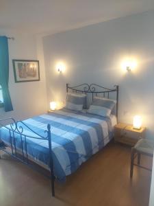a bedroom with a blue and white bed with two lamps at Maison Lavande in Sousceyrac +16 photos