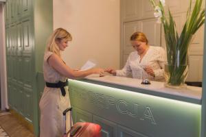 two women are standing at a reception desk at Villa Herkules - Adults Only in Świnoujście