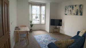 a living room with a blue couch and a tv at The Loy Guest Apartment in Cookstown