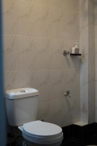 a bathroom with a toilet and a tiled wall at Elite Escape in Muchatha