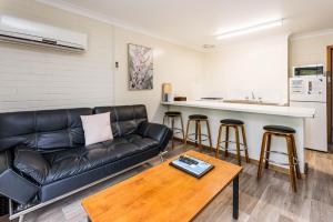 a living room with a black leather couch and a table at Emu Beach Chalets in Albany