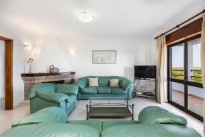 a living room with green couches and a tv at Casa Moura in Loulé