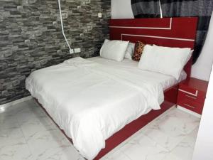 a bed with white sheets and pillows in a room at P M Serviced Apartments in Lagos