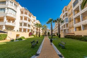 a brick walkway between two apartment buildings with benches at Las Dunas by Ĥ in Isla del Moral