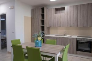 a kitchen with a wooden table and green chairs at Basilicata Host to Host - Le Muse in Stazione di Metaponto +41 photos