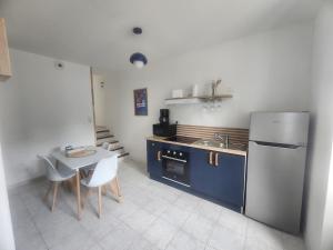 a kitchen with a refrigerator and a table with chairs at Le Carré Vert, appartement avec terrasse in Lamballe Armor