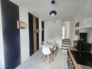 a kitchen with a white table and chairs in it at Le Carré Vert, appartement avec terrasse in Lamballe Armor +3 photos